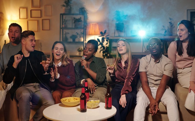 group-of-young-intercultural-friends-singing-karaoke-while-sitting-on-couch.jpg